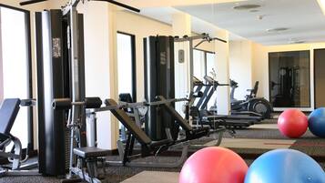 Uma academia com diversos equipamentos de ginástica, esteiras e bolas de exercício.