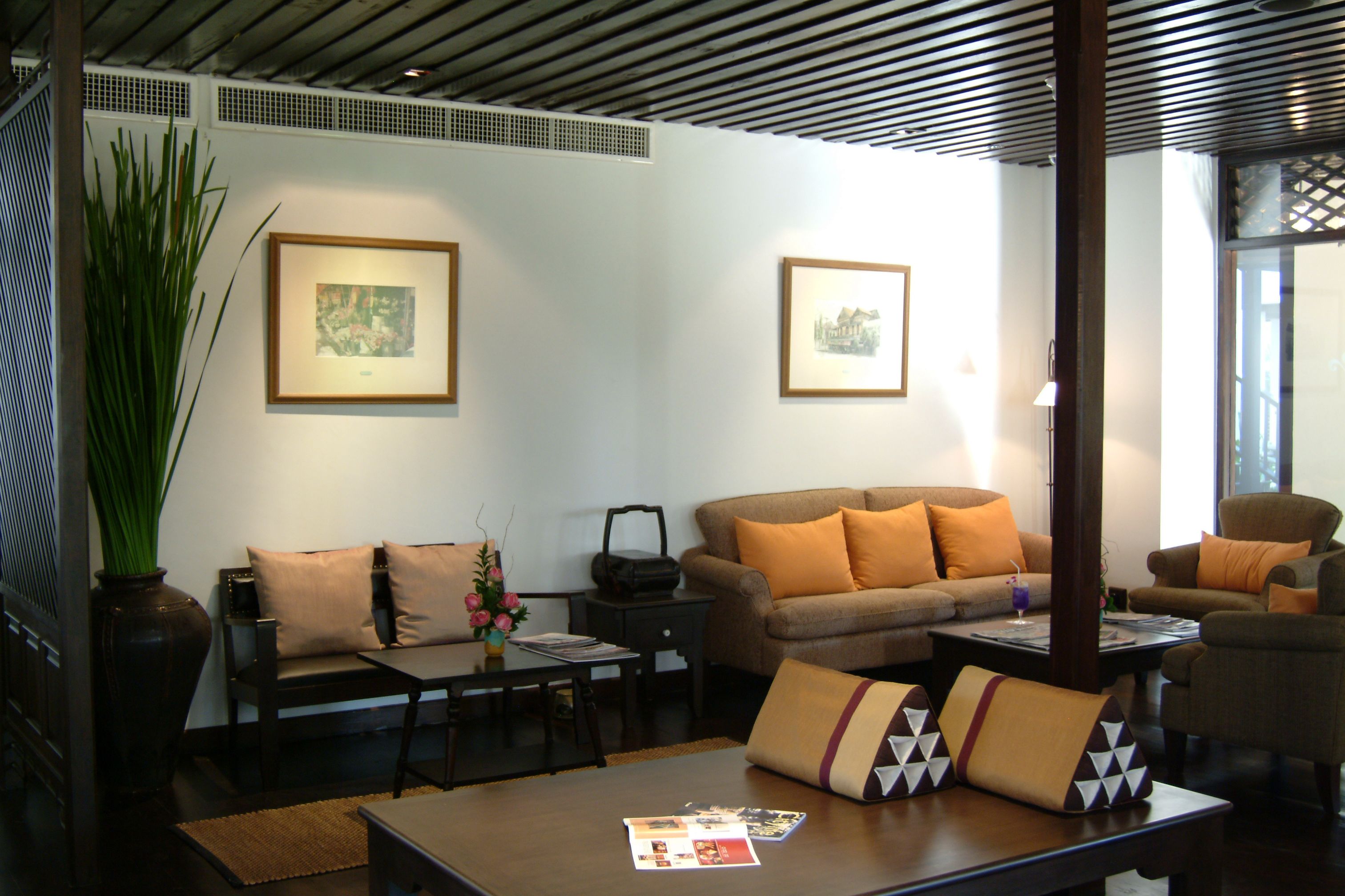 A living room with a sofa, armchairs, a coffee table, and two framed pictures on the wall.
