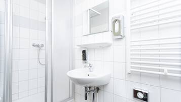 A modern bathroom with a white sink, a mirror, a towel rack, and a shower.