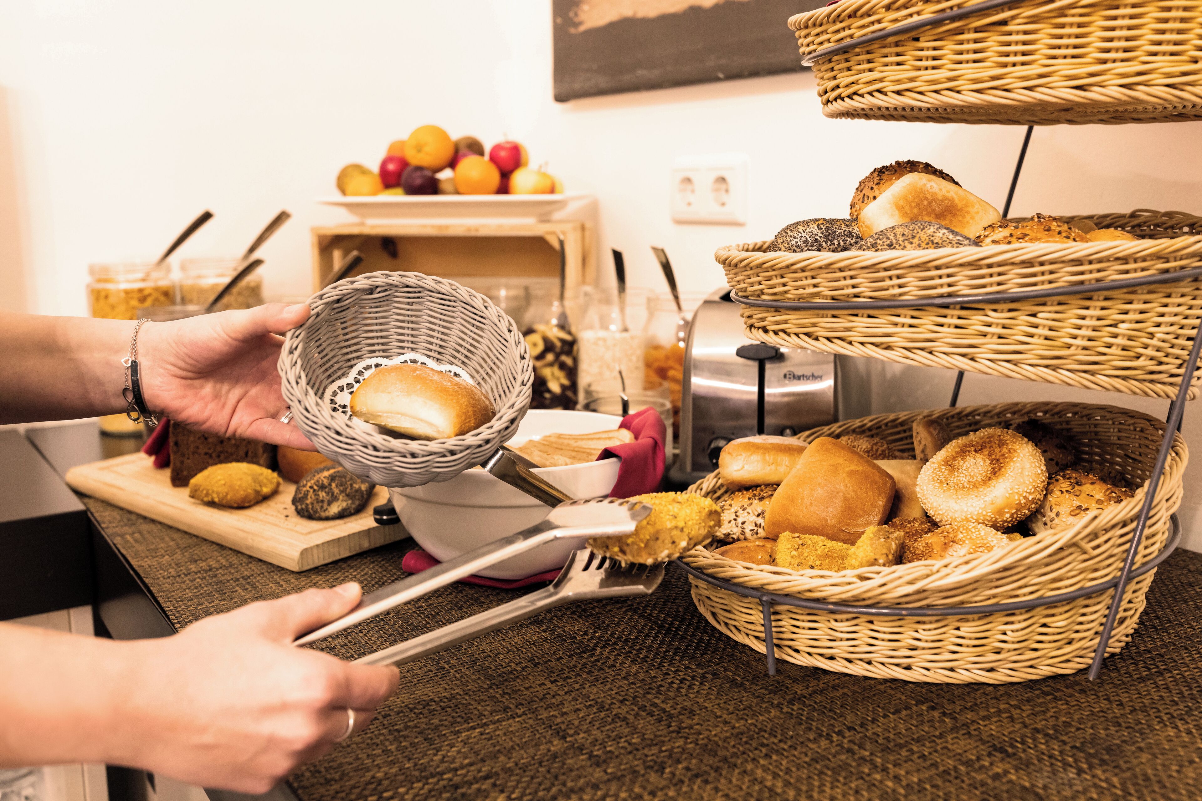 Mesa de buffet con varias cestas de pan y pastelería.