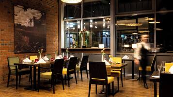 A restaurant with brick walls, wooden tables, and chairs.