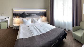 Ein Hotelzimmer mit Bett, Schreibtisch, Stuhl und einem großen Fenster mit Landschaftsblick.
