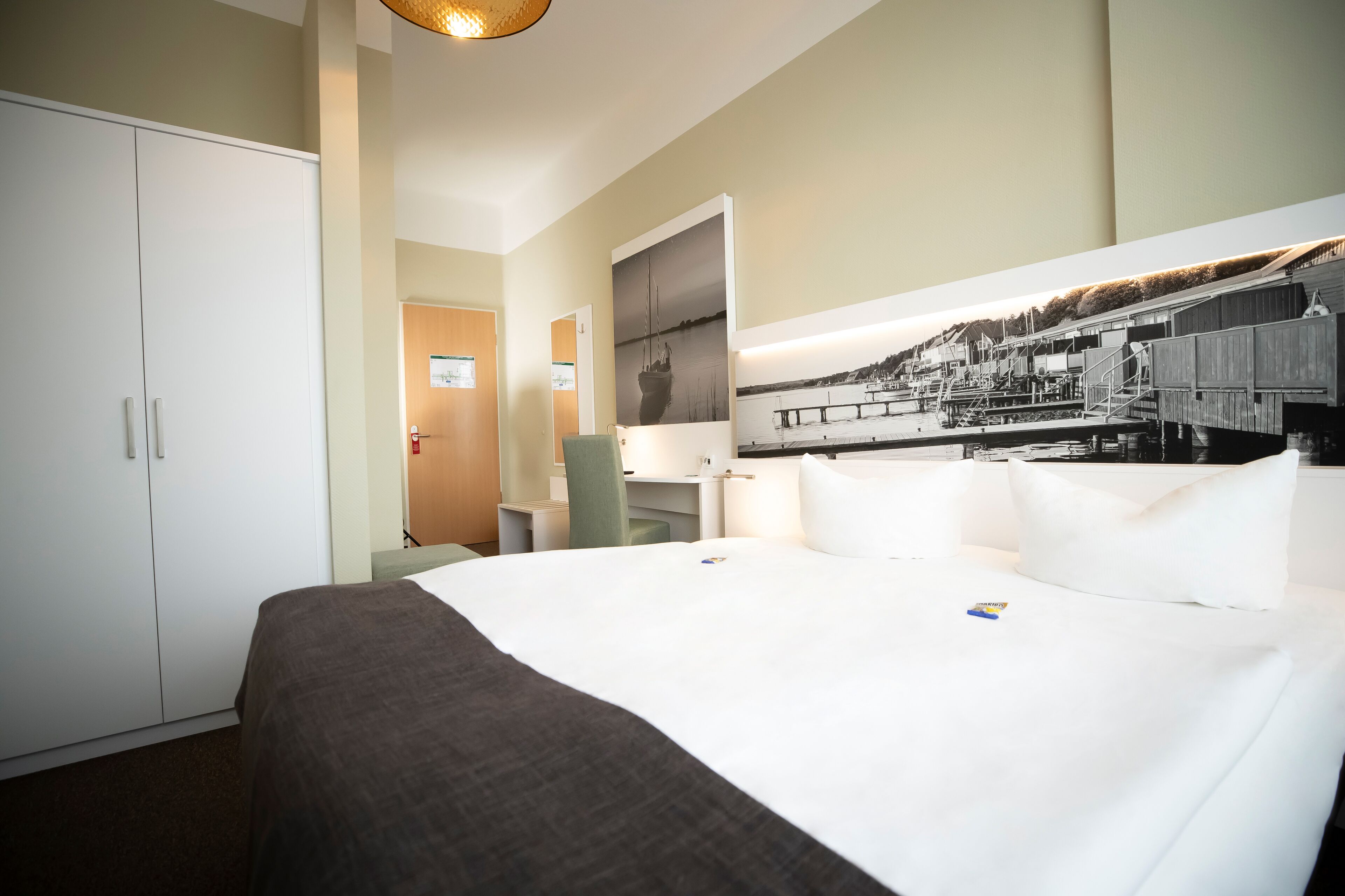 A hotel room with a large bed, a wardrobe, a desk, and a wall-mounted TV.