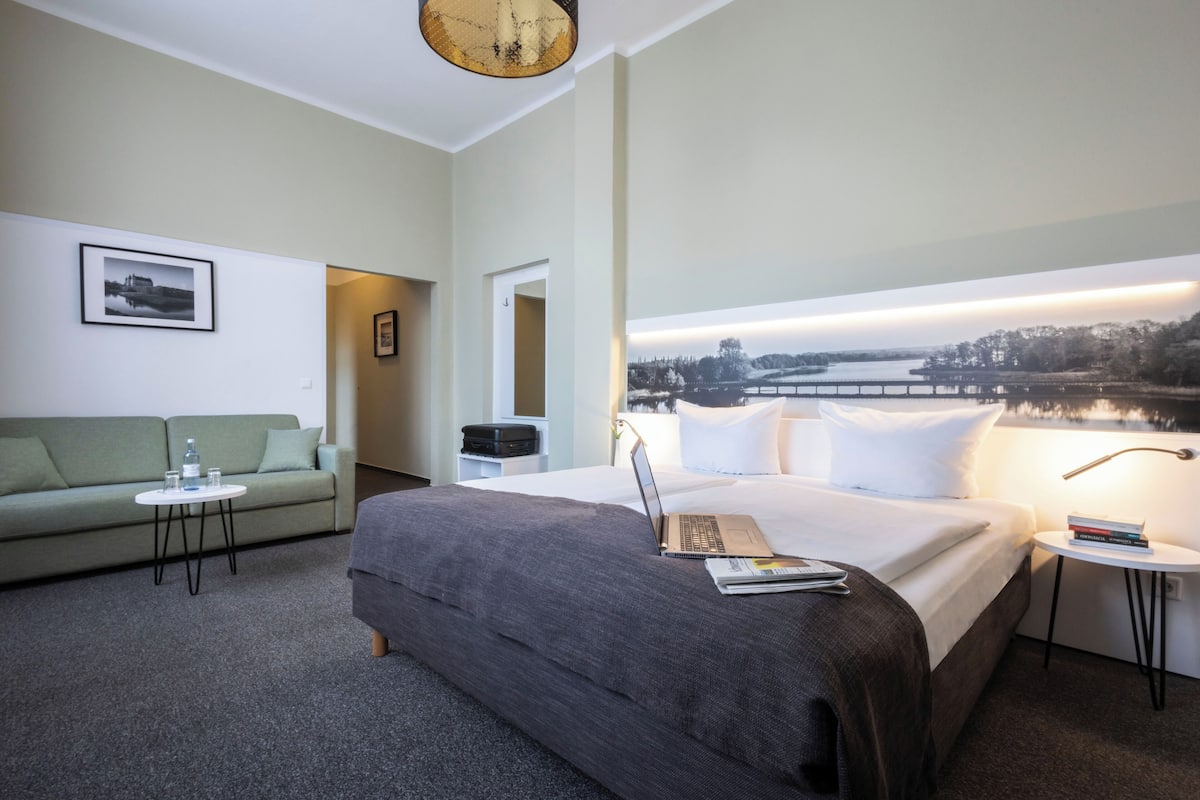 Una habitación de hotel con una cama, un sofá, una mesita y una mesita de noche.