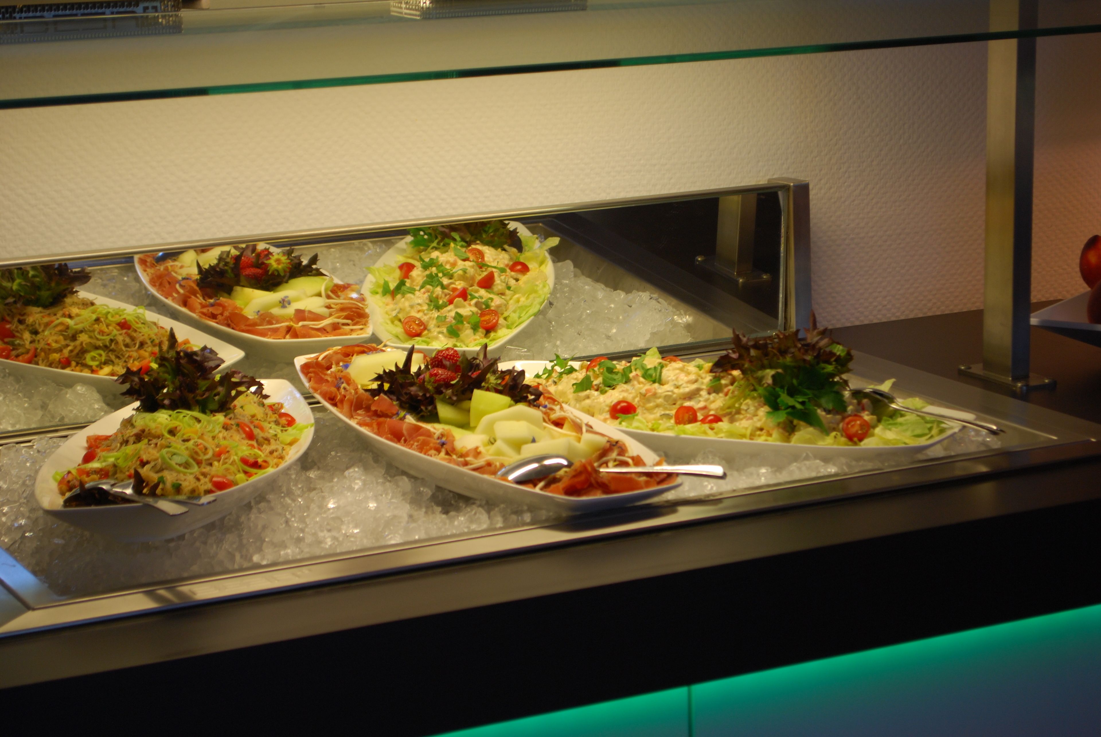 A buffet with various dishes on ice, including salads, meats, and vegetables.