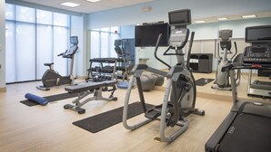 Un gimnasio con cintas de correr, elípticas y pesas sueltas.