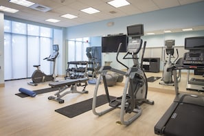 Une salle de sport équipée de tapis de course, de vélos elliptiques et de poids libres.