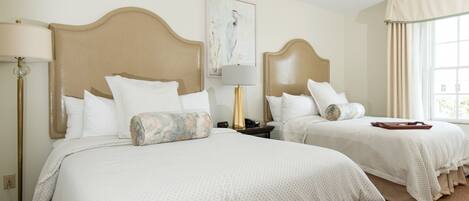 A hotel room with two beds, a painting on the wall, and a window with curtains.