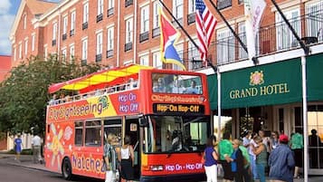A double-decker bus with "City Sightseeing" branding parked in front of a hotel.