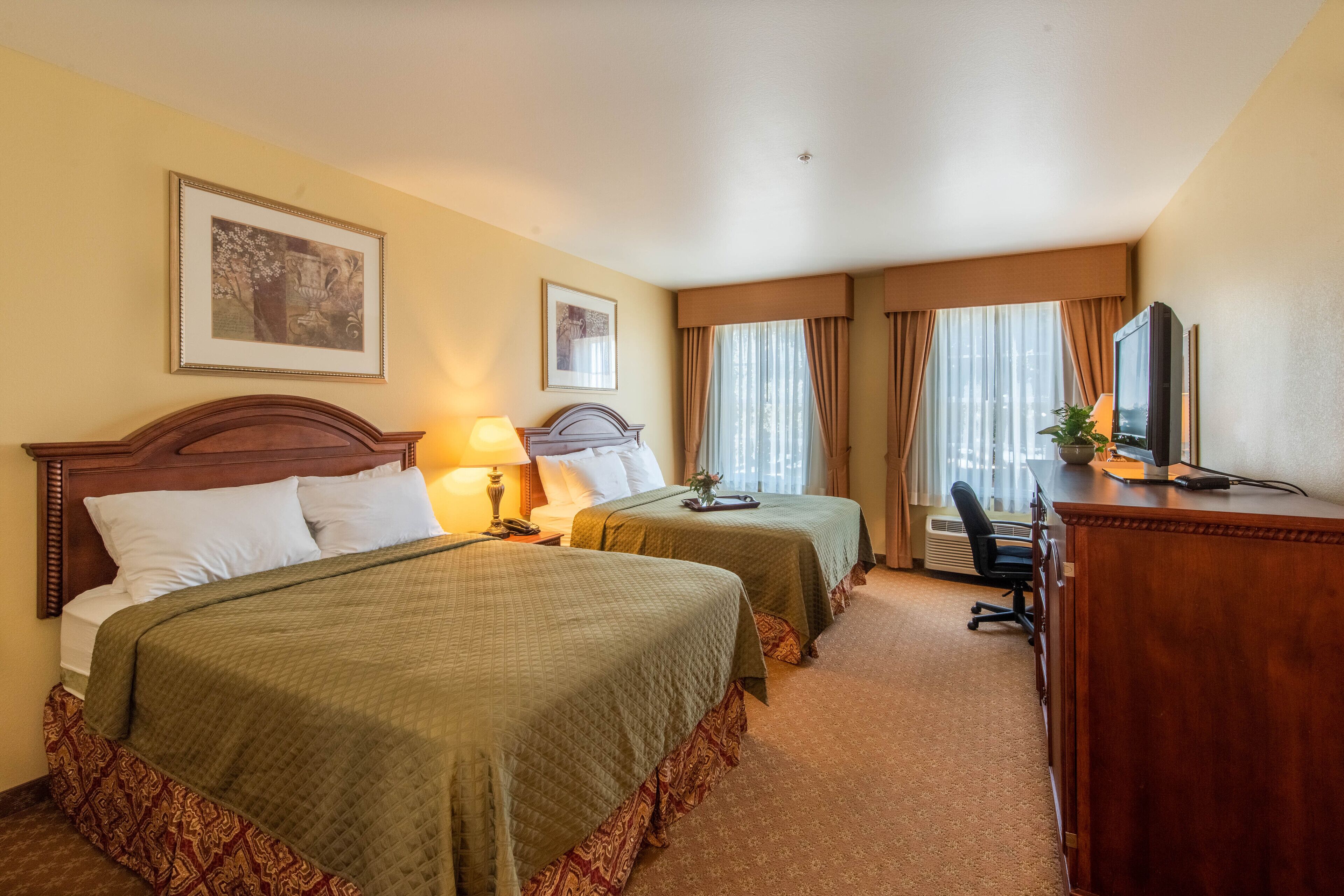 Une chambre d’hôtel avec deux lits, un bureau, une chaise et un téléviseur.