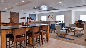 En hotellobby med en bardel, sittplatser och en kaffestation.