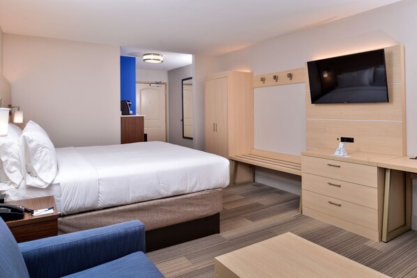 Una habitación de hotel moderna con cama, escritorio, televisor y armario.
