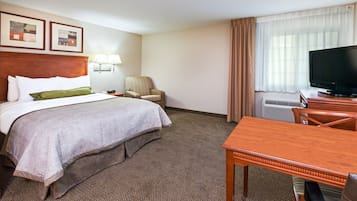 Una camera d'albergo con un letto, una scrivania, una sedia, una televisione e una finestra con tende.