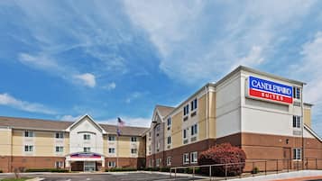 A hotel with a prominent 'CANDLEWOOD SUITES' sign, a parking lot, and a flagpole with the American flag.