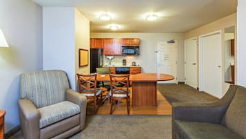 A compact living space with a kitchenette, a dining area with a table and chairs, and a seating area with a sofa and armchair.