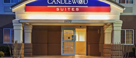 Entrada de un hotel con un cartel que dice 'CANDLEWOOD SUITES' y la dirección '11699'.