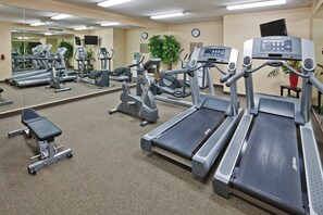 Uma academia com diversos equipamentos de exercício, incluindo esteiras, bicicletas ergométricas e aparelhos de musculação.