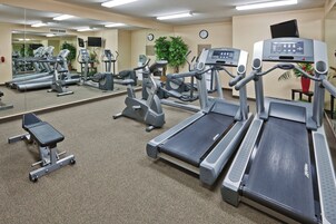 A gym with various exercise equipment including treadmills, stationary bikes, and weight machines.