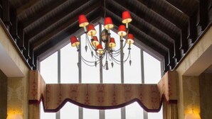 Un vaste salon doté d’une grande fenêtre, d’un lustre et offrant une vue sur la campagne.