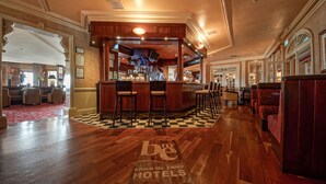 Un hall d’hôtel avec un bar, un sol à carreaux et des sièges.