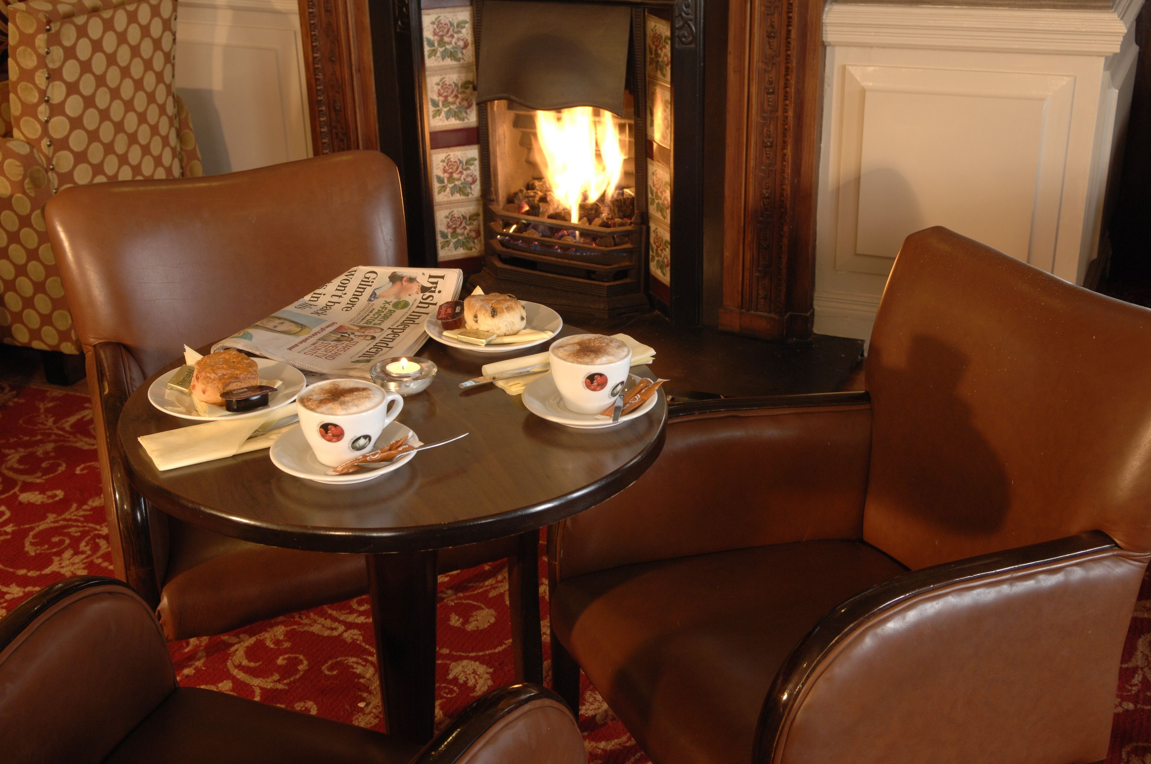 A cozy room with a fireplace, a table with a newspaper, and a plate of food.