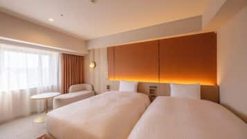 A hotel room with two beds, a small round table, a sofa, and a large window with curtains.