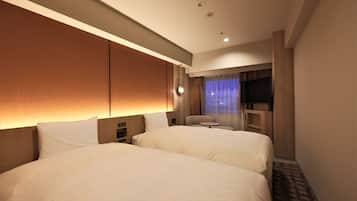 A hotel room with two beds, a desk, a chair, a TV, and a window with curtains.