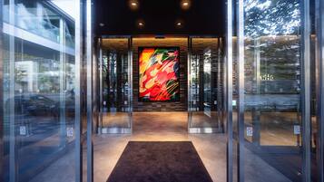 A modern building entrance with glass doors, a central art piece, and a carpeted floor.