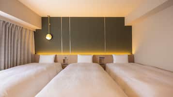 A hotel room with two beds, a bedside table, a lamp, and a curtain.