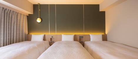 Une chambre d’hôtel avec deux lits, une table de chevet, une lampe et un rideau.