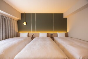 A hotel room with two beds, a bedside table, a lamp, and a curtain.