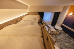 A hotel room with a large bed, a small seating area, and a window with curtains.