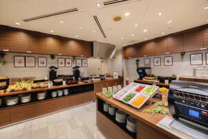 A buffet area with various food items and a self-service grill station.