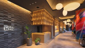 A modern hotel reception area with a wooden reception desk, a potted plant, and a reception desk with a digital display. - Canal City Fukuoka Washington Hotel (Fukuoka)