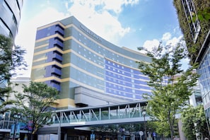 A modern hotel with a curved facade, multiple balconies, and a pedestrian bridge. - Canal City Fukuoka Washington Hotel (Fukuoka)