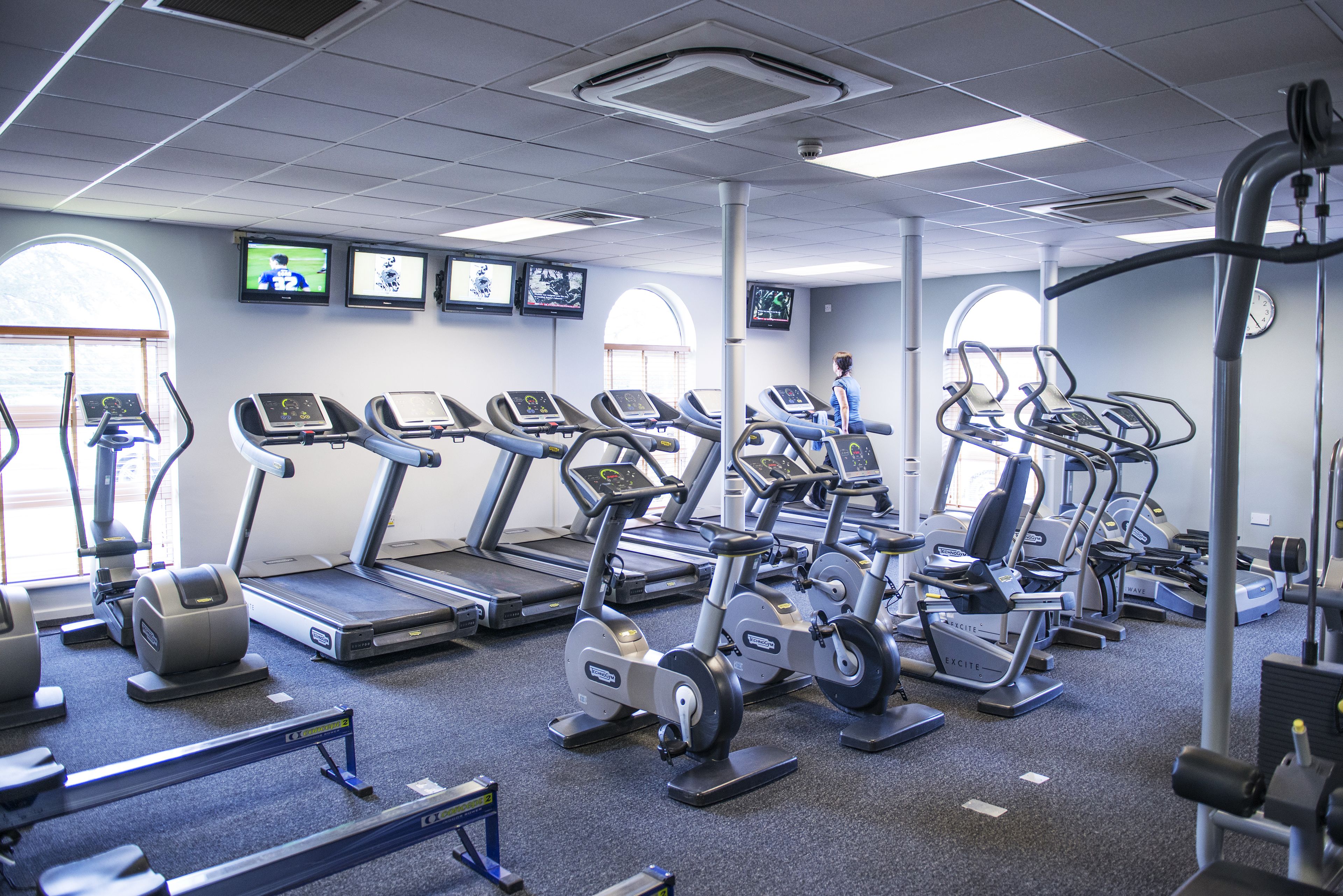 Un gimnasio con cintas de correr, elípticas y bicicletas estáticas.