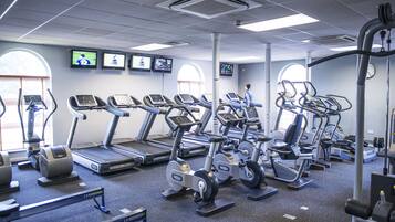 Un gimnasio con cintas de correr, elípticas y bicicletas estáticas.