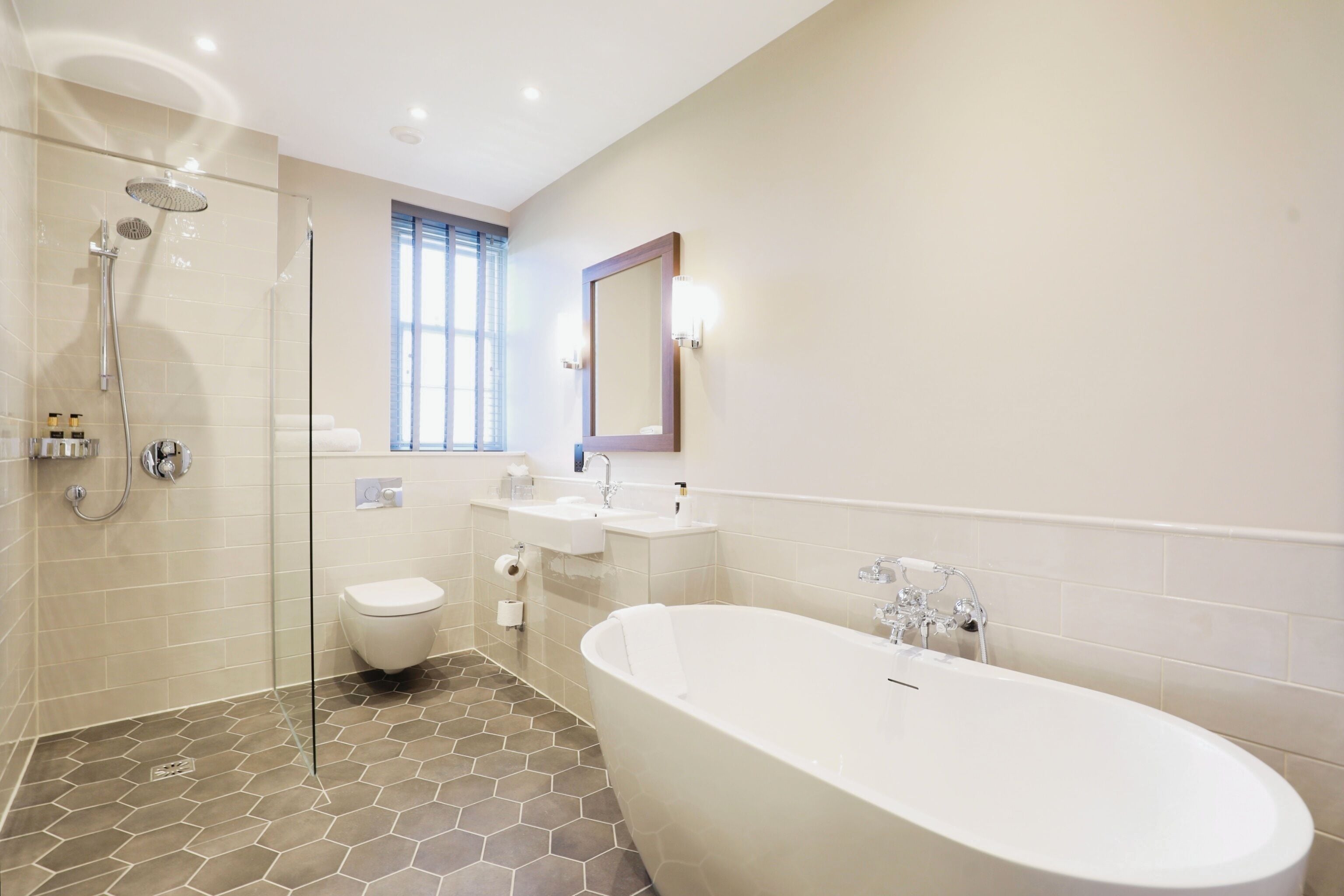 Un bagno moderno con doccia a vetro, vasca da bagno freestanding e un mobile lavabo con specchio.