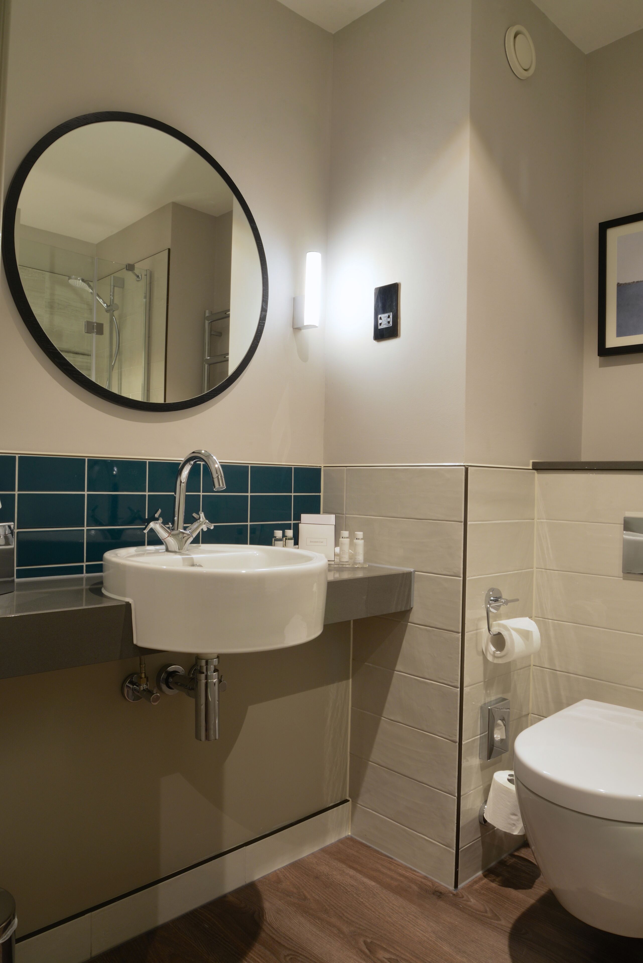 A modern bathroom with a white sink, a round mirror, and a toilet.