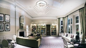 A spacious living room with a fireplace, a large bookcase, and a chandelier.