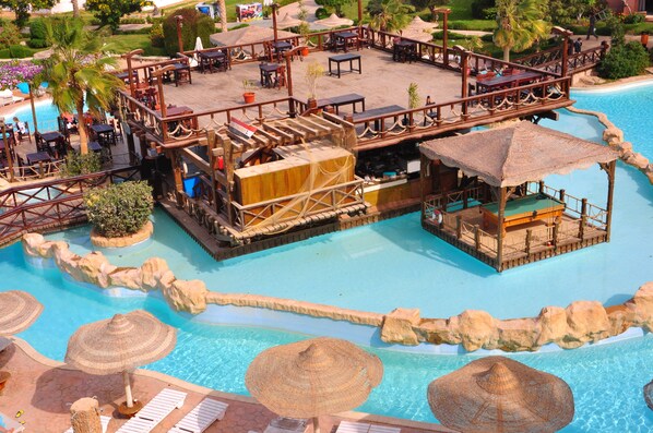 A pool area with a wooden deck, lounge chairs, and umbrellas. - Rehana Sharm Resort - Aqua Park & Spa - Families & Couples Only (Sharm El Sheikh)