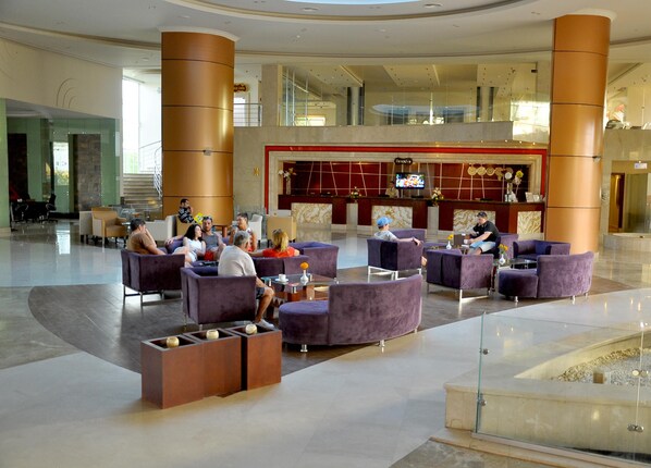 A spacious lobby with seating areas, a reception desk, and a large screen displaying content. - Rehana Sharm Resort - Aqua Park & Spa - Families & Couples Only (Sharm El Sheikh)