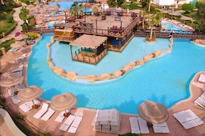 A large swimming pool with a central island, surrounded by lounge chairs and umbrellas. - Rehana Sharm Resort - Aqua Park & Spa - Families & Couples Only (Sharm El Sheikh)