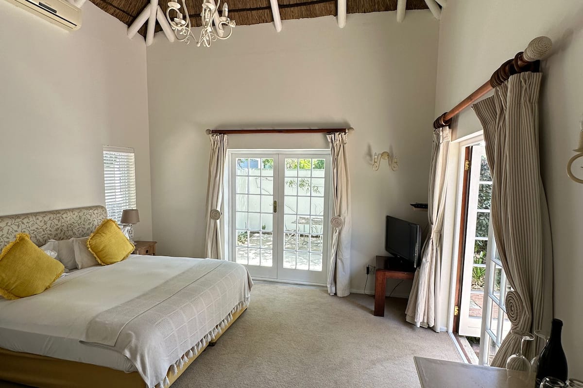 A bedroom with a bed, a sofa, a TV, and a window with curtains.