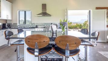 A modern kitchen with a central island, bar stools, and a view to a balcony.