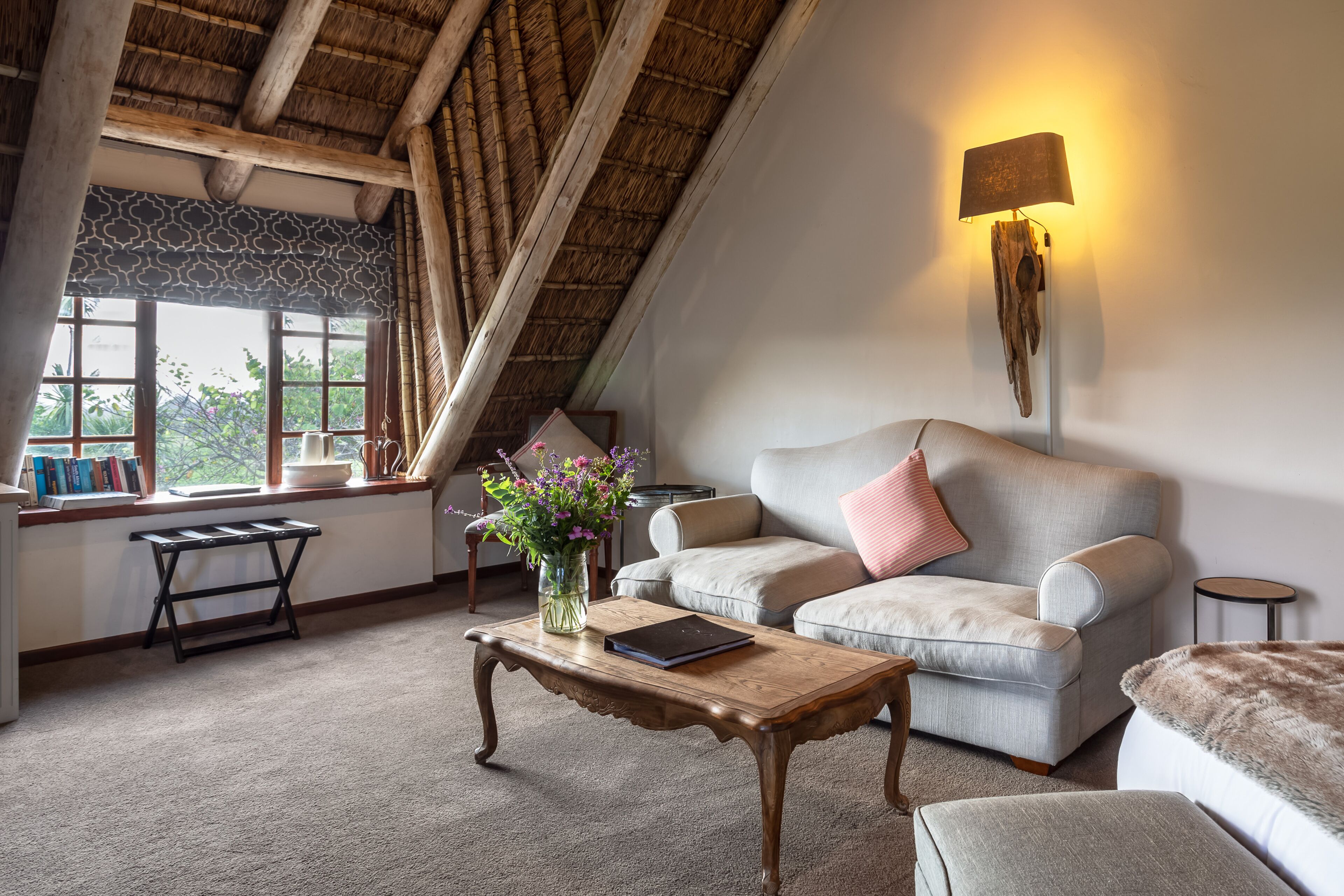 A cozy living room with a high ceiling, a sofa, a coffee table, and a lamp.