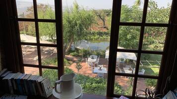 Vista a través de una ventana que muestra una mesa con libros y una jarrón blanco.
