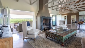 A spacious living area with a fireplace, comfortable seating, and a view of the outdoors. - Wedgeview Country House & Spa (Stellenbosch)
