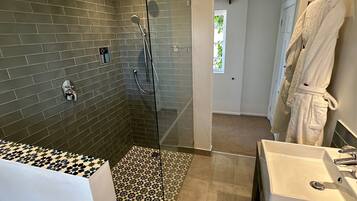 A modern bathroom with a glass-enclosed shower, a white bathtub, and two sinks.