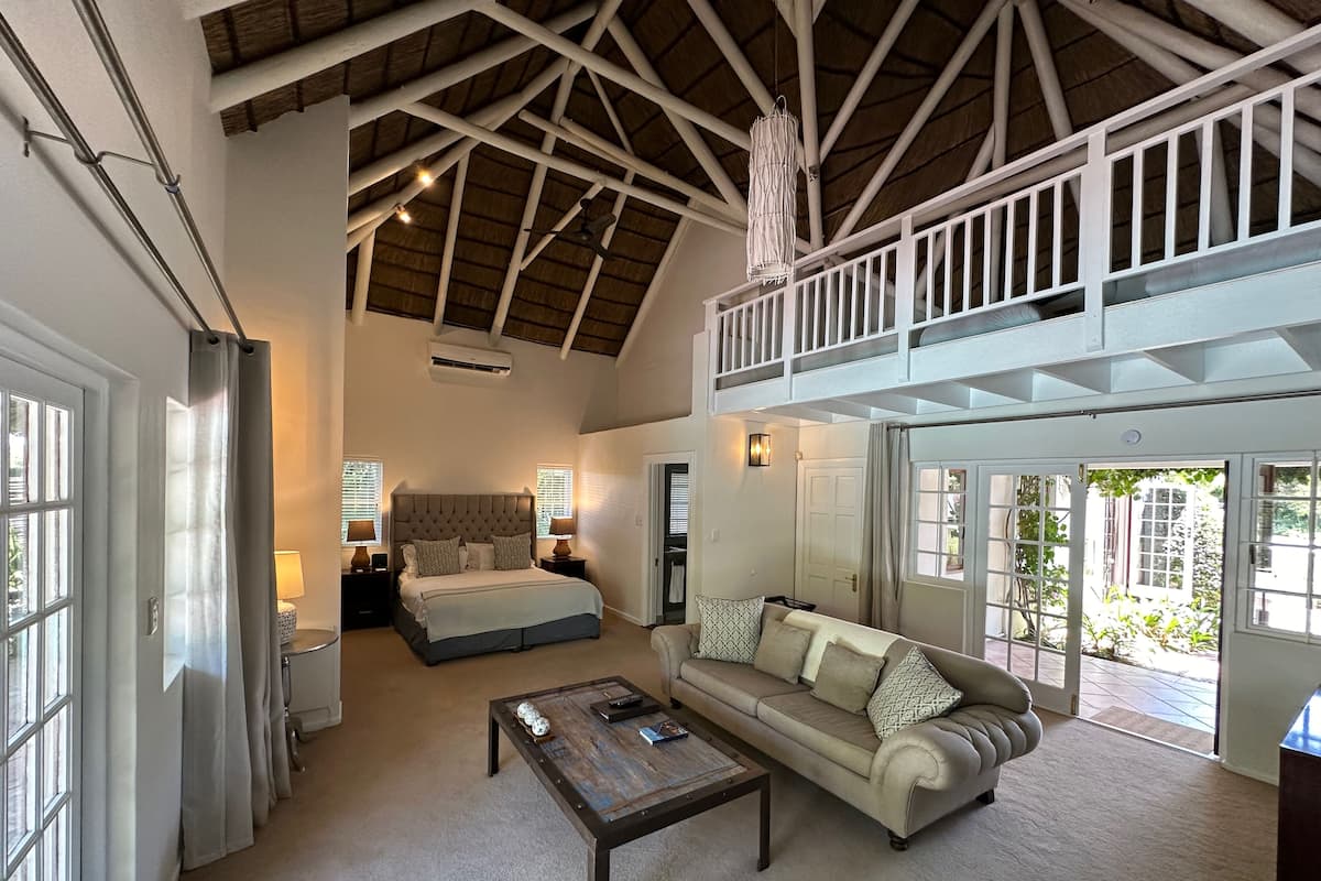 A spacious room with a high ceiling, a bed, a sofa, and a coffee table.